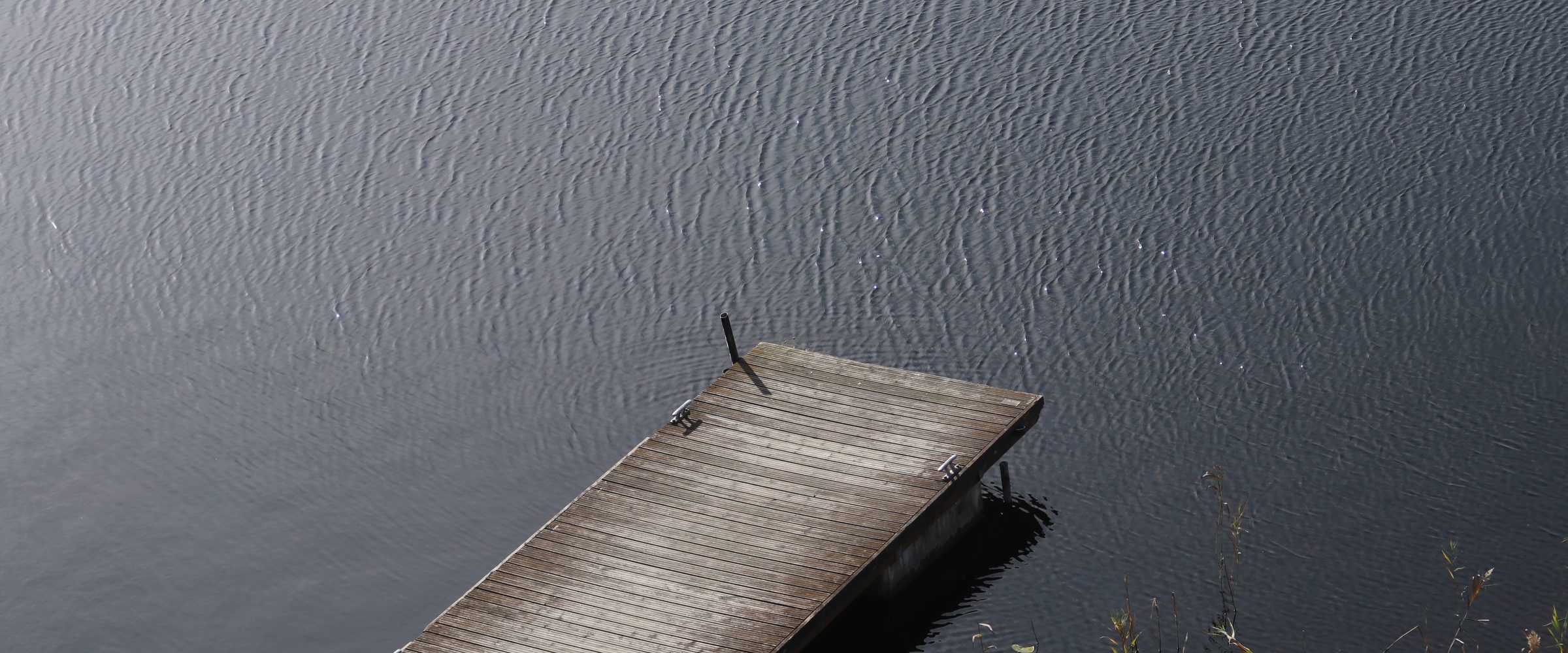 The far dock on still gray water, early in the morning