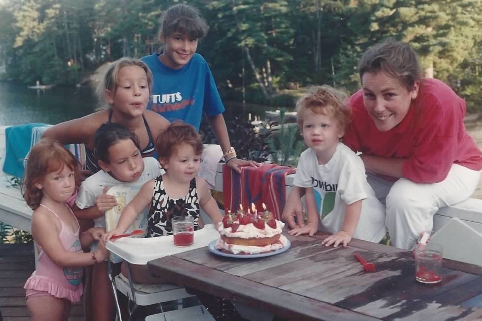A birthday cake on the deck, kids all around