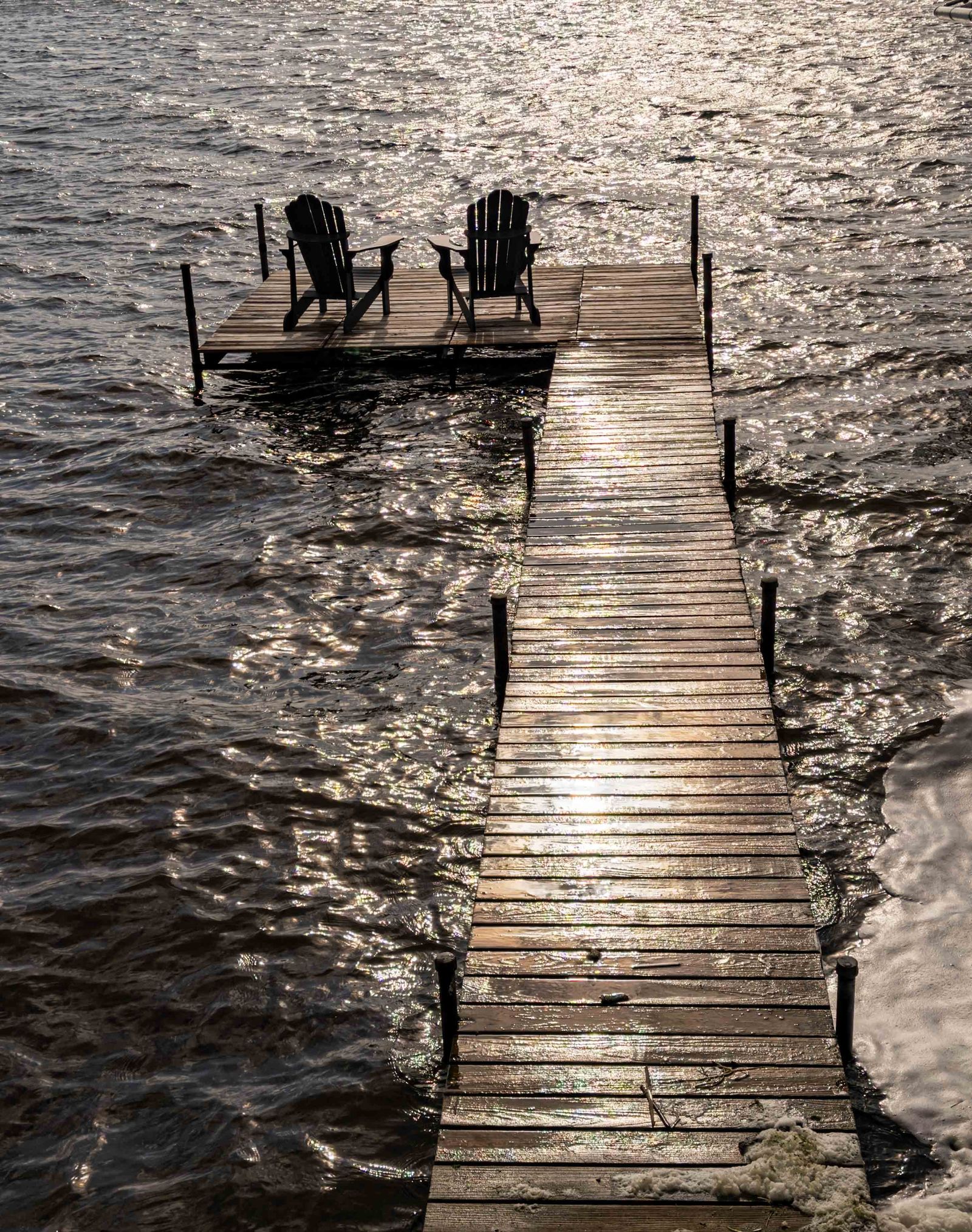 Two chairs at the end of a pier, waiting