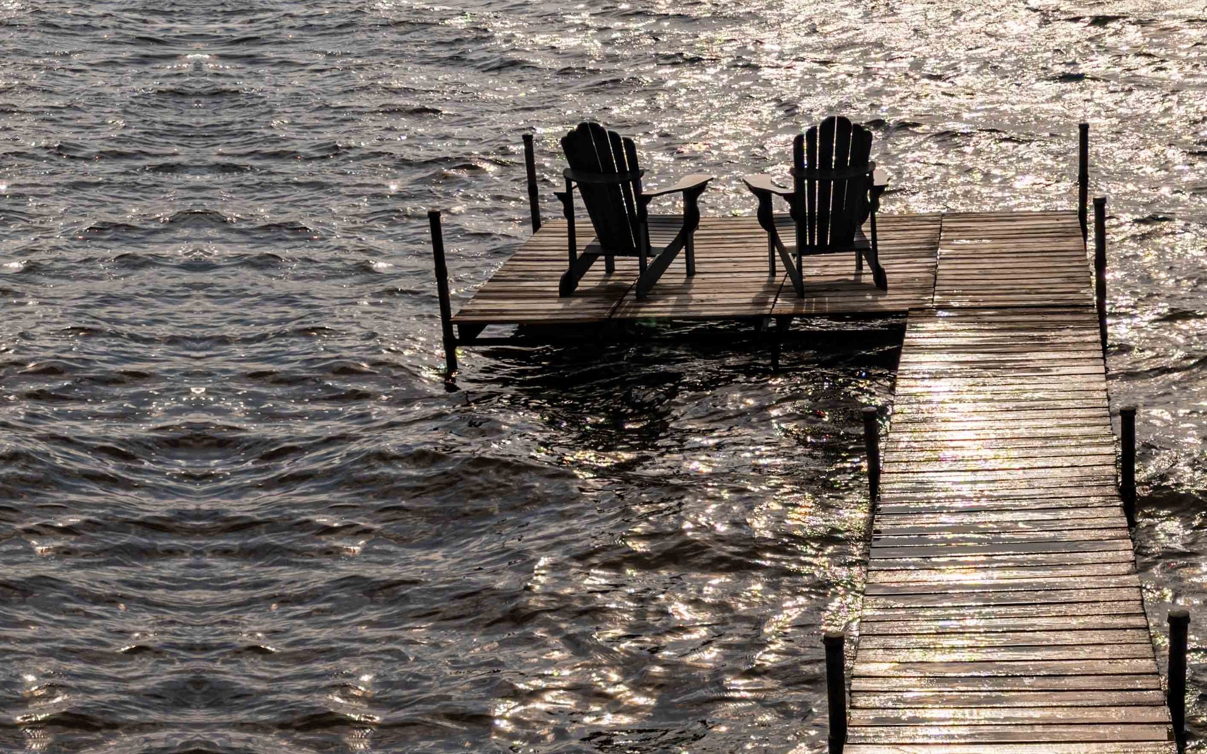 Two chairs at the end of the dock in golden evening light
